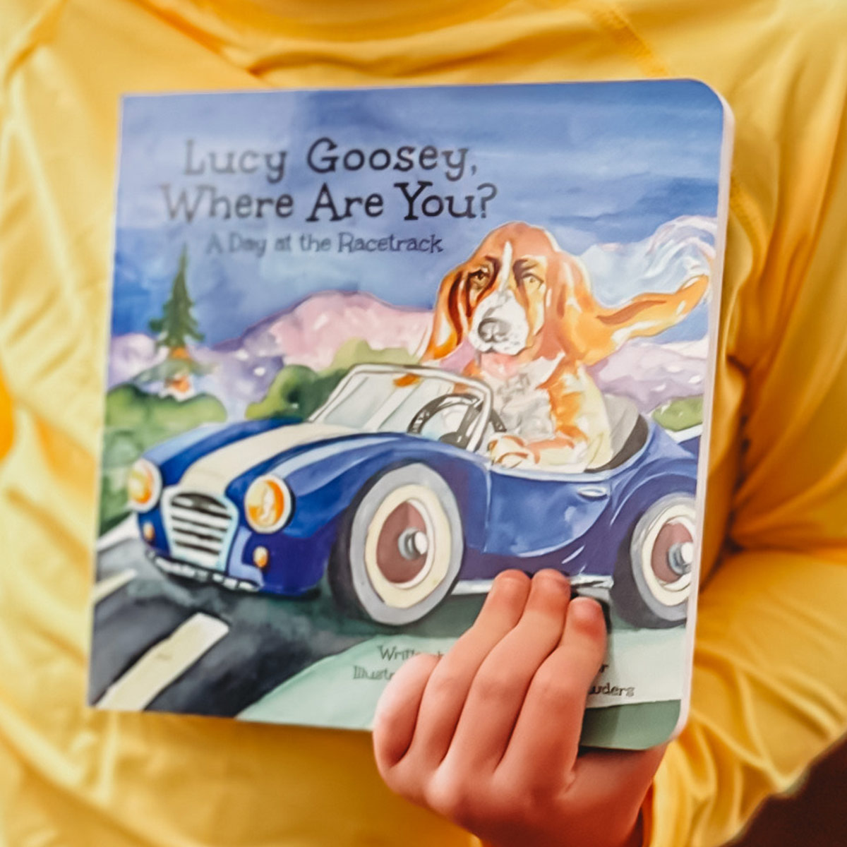 Close-up photo of "Lucy Goosey, Where Are You?" board book cover with dog driving a race car